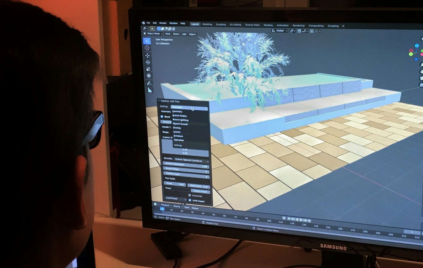 Designer works on 3D modeling software displaying a digital tree.