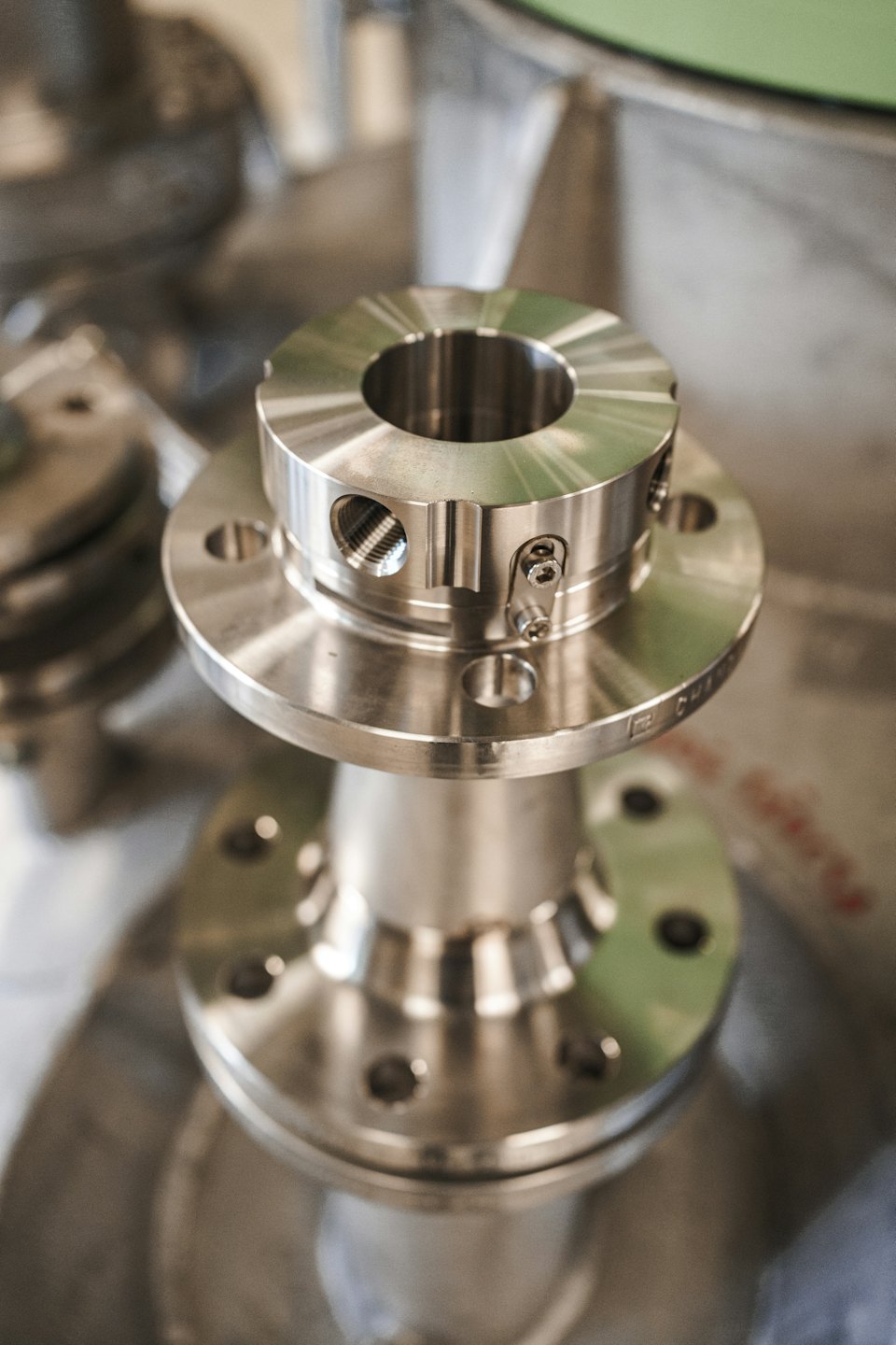 Polished silver industrial component with shaft and bolt holes.